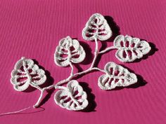 four white crocheted leaves on a pink surface