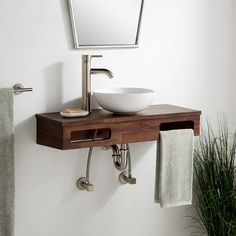 a bathroom sink sitting under a mirror next to a towel rack and potted plant