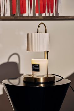 a table lamp sitting on top of a black table next to a white and gold lamp