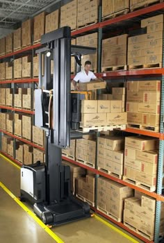 a man in a warehouse with boxes on the shelves and a forklift behind him