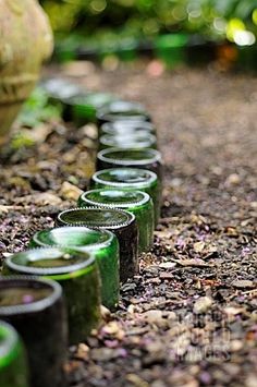 there are many green jars lined up on the ground with rocks in front of them