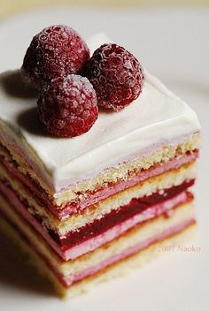 there is a piece of cake with raspberries on top and white frosting