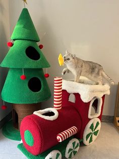 a cat sitting on top of a train next to a christmas tree and other decorations