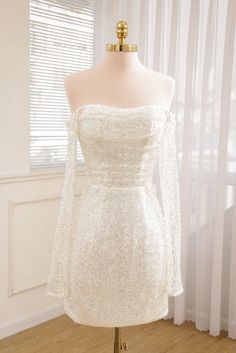 a white dress on a mannequin stand in front of a window with curtains