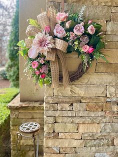 a wreath with pink flowers hanging on a stone wall