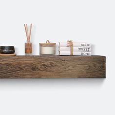 a shelf with candles, books and other items on it in front of a white wall