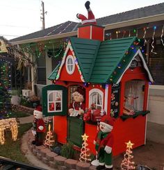 a house with christmas decorations and lights on the front yard, including santa's helpers