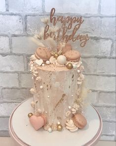 a birthday cake decorated with shells and seashells on a white pedestal in front of a brick wall