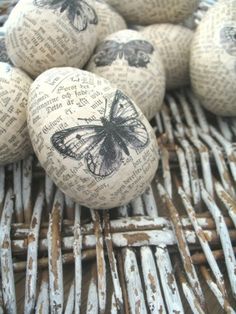 some eggs with butterflies on them are sitting in a wicker basket filled with newspaper pages