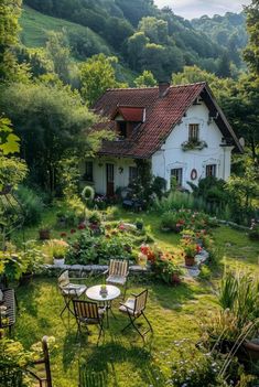 a house in the middle of a lush green field with chairs and tables around it