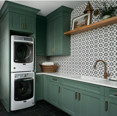 a washer and dryer sitting in a kitchen next to green cabinets with black flooring