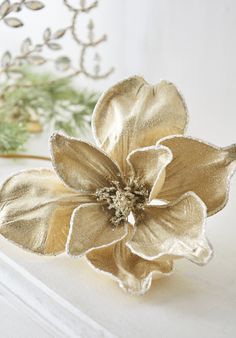 a close up of a gold flower on a white surface with other flowers in the background