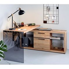 a desk with drawers and a lamp on it in a white room next to a plant