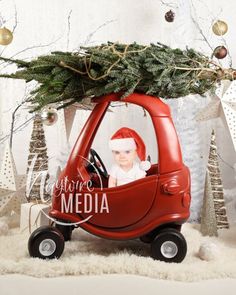 a baby in a red car with a christmas tree on the top is surrounded by decorations