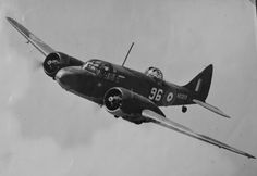 black and white photograph of an old airplane flying in the sky