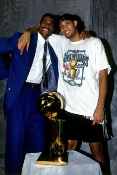 two men standing next to each other in front of a trophy and posing for the camera