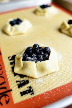 small pastries on a baking sheet with blueberries and blackberries in the middle