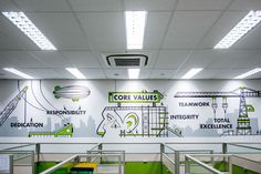 an office with green and white graphics on the wall, along with stairs to other rooms