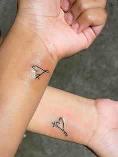 two people holding hands with tattoos on their arms and wrist, one has a heart and the other has an arrow