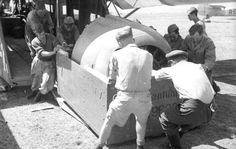 an old black and white photo of some men loading something into a small plane on the ground