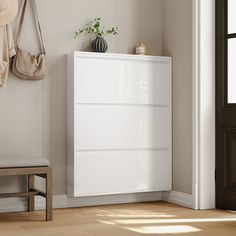 a white cabinet sitting in the corner of a room next to a bench and potted plant