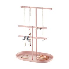 a pink jewelry rack with three rings and two bracelets hanging from it's sides