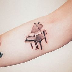 a small tattoo on the arm of a person with a piano and musical notes behind it