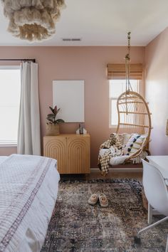 a bedroom with pink walls and a hanging hammock chair next to the bed