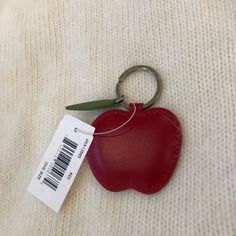 an apple shaped keychain with a tag attached to it