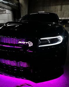 the front end of a black car with purple lights on it's grilles