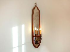 a mirror mounted to the side of a wall with two lit candles in front of it