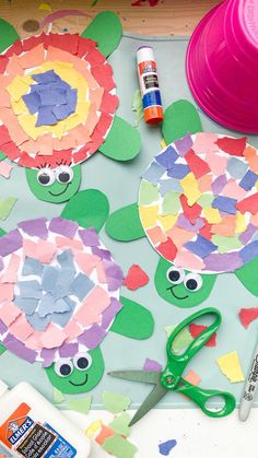 paper plates and scissors are sitting on a table with cut out flowers, turtle faces, and other crafting supplies