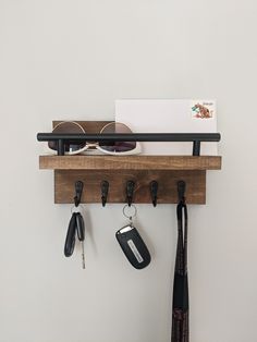 a wooden shelf with keys and sunglasses hanging from it's hooks on the wall