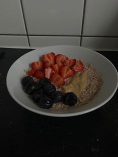 a white bowl filled with oatmeal and fruit on top of a counter