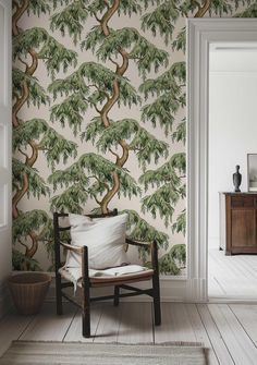 a chair in front of a wallpaper with a tree on it and a potted plant next to it