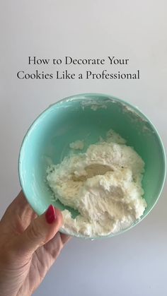 a hand holding a blue bowl filled with white powder on top of a white table