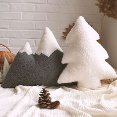 two pillows and a pine cone on a bed