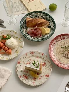 four plates with food on them sitting on a table next to glasses and utensils