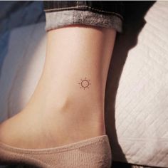 a woman's foot with a small sun tattoo on the left side of her ankle