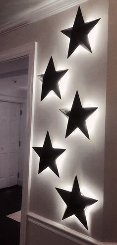 five black stars are mounted on the wall in front of a white door with lights