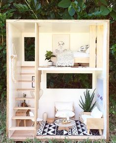 a doll house with stairs and furniture in the grass next to some trees, bushes and plants