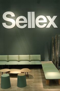 a green couch sitting in front of a wall with the word sellex on it