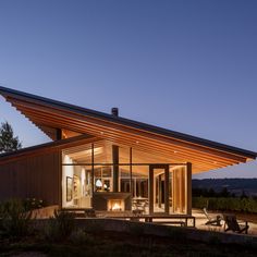 a modern house with an open patio and covered in lights at night, lit up by the sun