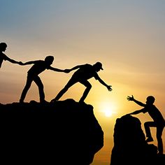 three people holding hands while standing on top of a mountain at sunset or dawn with the sun setting behind them