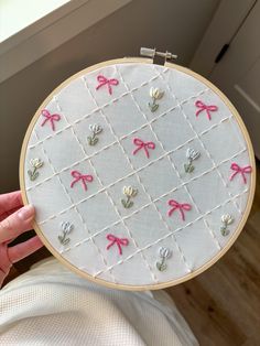 a person holding up a cross - stitch pattern with pink bows on it