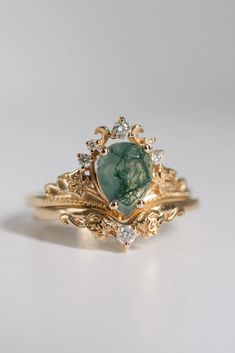 a gold ring with a green stone surrounded by diamonds