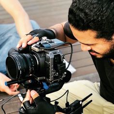 a man sitting on the ground with a camera in his hand and another person behind him