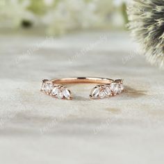 a rose gold ring with three diamonds on it and a pine branch in the background