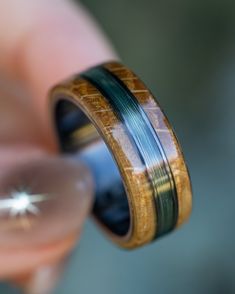 a person is holding a ring with wood and green inlays on the inside