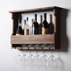 wine glasses and bottles are lined up in a wooden holder on the wall next to empty wine glasses